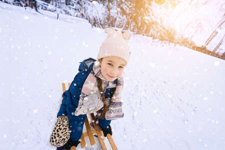 Two children ride on wooden retro sled on sunny winter day. Active winter outdoors games. Winter...