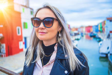 Happy traveler woman having fun near colorful houses on Burano island in Venetian lagoon. Travel and vacation in Italy concept. Lifestyle travel moments in the beautiful italian cityの写真素材