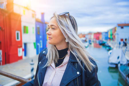 Happy traveler woman having fun near colorful houses on Burano island in Venetian lagoon. Travel and vacation in Italy concept. Lifestyle travel moments in the beautiful italian cityの写真素材