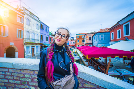 Happy traveler woman having fun near colorful houses on Burano island in Venetian lagoon. Travel and vacation in Italy concept. Lifestyle travel moments in the beautiful italian cityの写真素材