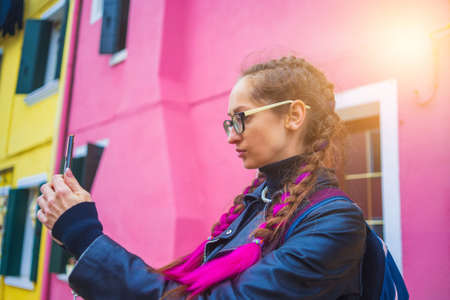 Traveler blogger taking selfie photo near colorful houses on Burano island in Venetian lagoon....