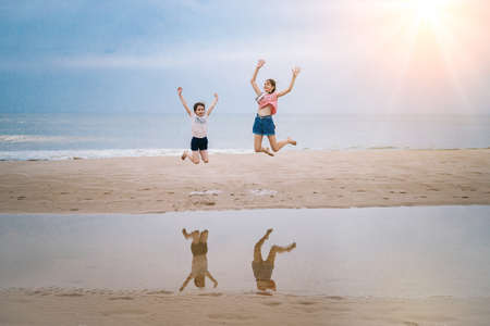 happy girl having fun on tropical beach and running and splashing at shallow water, jumping into air on sea coast at sunny day time. Summer travel and vacation concept.の写真素材