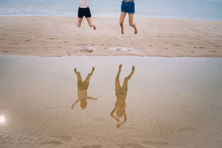 happy girl having fun on tropical beach and running and splashing at shallow water, jumping into air on sea coast at sunny day time. Summer travel and vacation concept.の写真素材