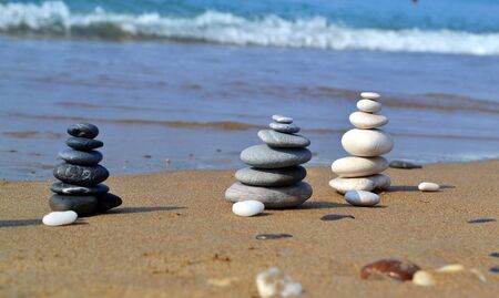 Black, gray and yellow stone zen towers on the sand, selective focus on the beach backgroundの写真素材