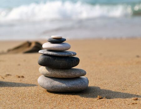 Small Zen style tower made of different sizes and color stones, selective view on the blurred beach backgroundの写真素材