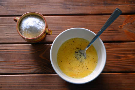 Raw yolks with milk and spices in a ceramic bowl - making a scrambled eggsの写真素材