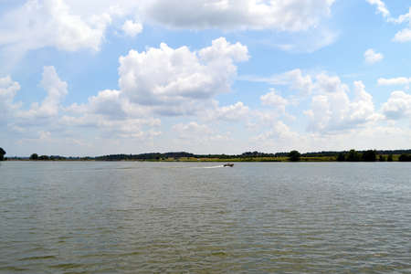 View of calm lake with single launch under the cloudy skyの写真素材