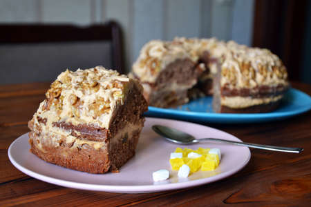 Tasty home baked cake with walnuts, candied fruits, cocoa and custard, selective focus on the kitchen tableの写真素材
