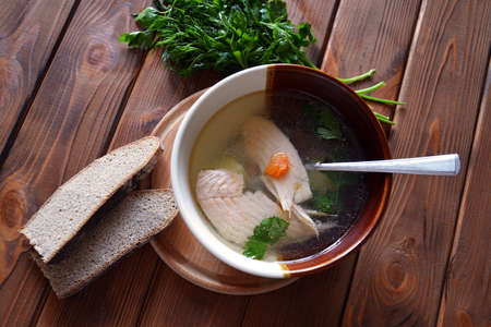 Hot salmon soup with carrot, green parsley, dill and rye bread on the wooden tableの写真素材