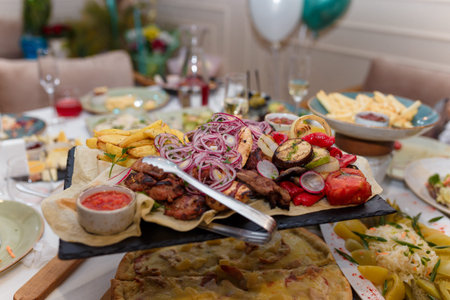 Festive dishes with grilled meat and vegetables, tomato, onions, potatoes. Wedding or birthday table...
