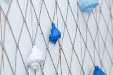 Thematic sea party decorations, blue and white painted sea shells hanging on fish net. Boy birthday party for child.の写真素材
