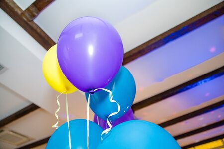 Blue, violet and yellow helium balloons at the ceilingの写真素材