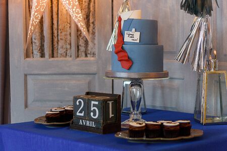 Candy bar with cupcakes, birthday cake with suit and tie design for a teenage boy, the Russian inscription reads Create Yourself. Cubic calendar with date 25 April.の写真素材
