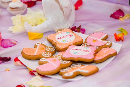 Pram shaped gingerbread cookies on white plate. Candy bar with sweets for girl birthday party. Russian inscription reads name Katusha.の写真素材