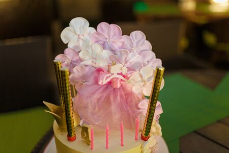 Pink girlish cake with flowers , candles and princess figure in crown.の写真素材