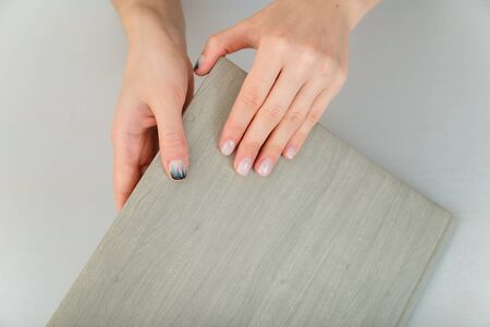 Female hands with fir-tree forest manicure holding leather covered album or notebook on white background. Christmas or winter nail art. Hands care, fingernails design, beauty and health concept. の写真素材