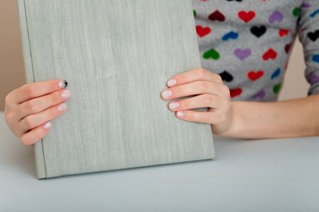 Female hands with fir-tree forest manicure holding leather covered album or notebook on white background. Christmas or winter nail art. Hands care, fingernails design, beauty and health concept. の写真素材