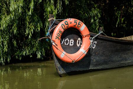 Vilkovo, Ukraine - August 2019. Old fishing boat with lifebuoy on river on green background.の写真素材