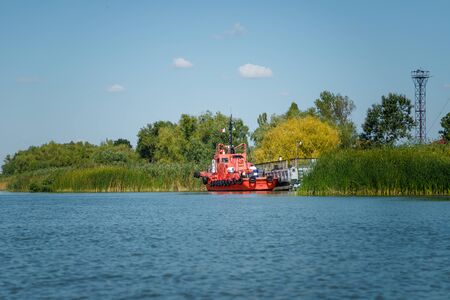 Vilkovo, Ukraine - August 2019. Red motor boat with tyres on river on green background.の写真素材