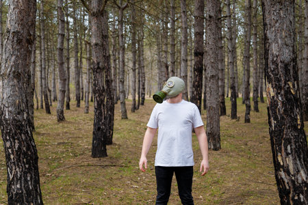 Man in white T-shirt and gas mask in pine forest. Enviromental protection, ecology, Earth saving,...