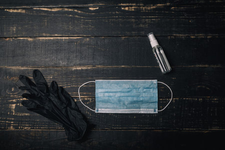 Medical gloves, gauze mask and sanitizer on black wooden background. Coronavirus Covid 2019,...