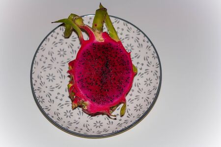 Fresh exotic halved pitaya or pitahaya costaricensis, dragon fruit on plate on white background.の写真素材