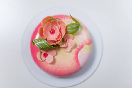 Soft focused shot of mirror glaze birthday cake with pink flowers on white background. Sweet festive pastry for girl or woman. Place for text.の写真素材