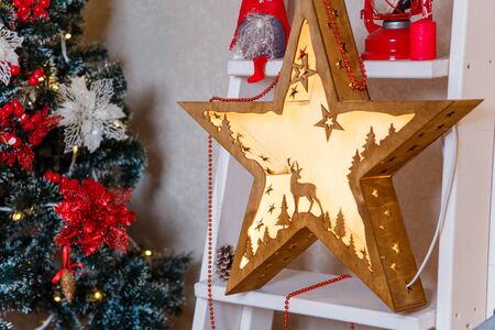 wooden decorative star with reindeer on the decorated fir tree background. Merry Christmas, Happy New Year and winter holidays concept.の写真素材