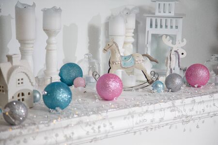 Christmas decorations, silver, blue and pink bulbs, white candles, wooden house and rocking horse toy standing on the white surface.
Merry Christmas, Happy New Year and Winter holidays concept.の写真素材