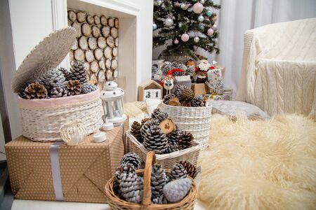 Christmas living room interior with decorated fir-tree, fireplace, white armchair, fluffy carpet, presents, baskets with pine cones.
Merry Christmas, Happy New Year and Winter holidays concept.の写真素材