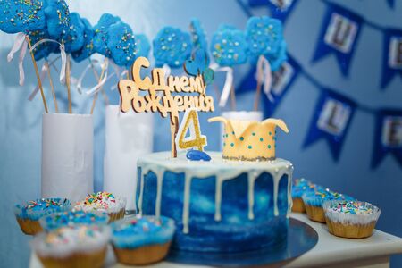 Soft focused shot of blue colored candy bar. Muffins with sprinkles, birthday cake with mastic crown, number 4 and inscription Happy Birthday. Four years old birthday party.の写真素材