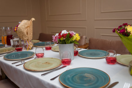 Festive table setting with autumn flowers bouquets, chrysanthemums, plates, cutlery, napkins, salt and pepper pots and wine or juice in glasses.の写真素材