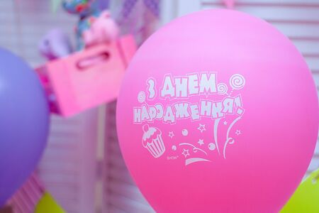 Pink helium balloon. Festive room interior, birthday surprise. Inscription on balloons in Ukrainian - Happy Birthday.の写真素材