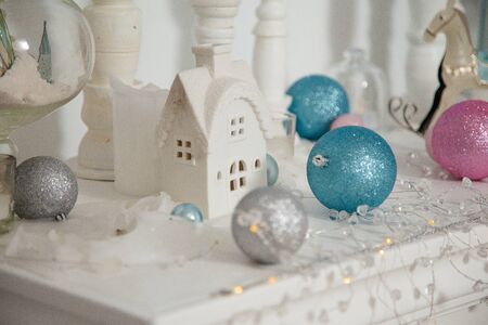 Christmas decorations, silver, blue and pink bulbs, white candles, wooden house and rocking horse toy standing on the white surface.
Merry Christmas, Happy New Year and Winter holidays concept.の写真素材