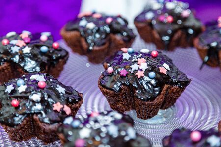 Candy bar with glazed muffins and sprinkles on purple background. Festive sweets for birthday party.の写真素材