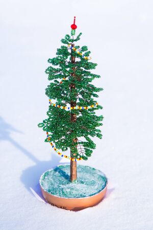Decorative beaded fir tree on snow surface backgroundの写真素材
