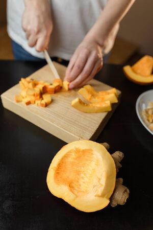 Woman chopping pumpkin on kitchen board, only hands visible. Autumn seasonal vegetables cooking. Healthy eating habits, organic vegetarian food concept. の写真素材
