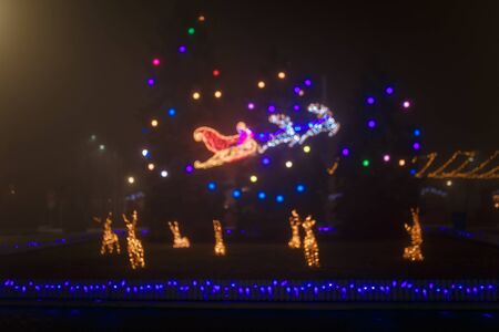 Unfocused night shot of Christmas reindeers and garland lights bokeh in the city. Happy New Year, Merry Christmas, winter holidays concept.の写真素材