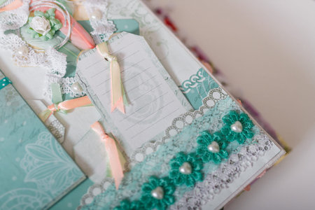 Soft focused close up shot of scrapbooking photo album page with paper decorative elements, flowers,...