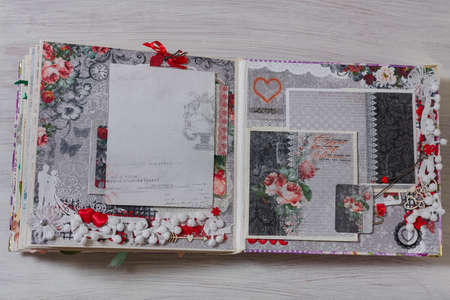 Scrapbooking wedding photoalbum spread with black and red paper decorative elements, flowers, beads, tapes, ribbons, hearts and frames for phographs.の写真素材