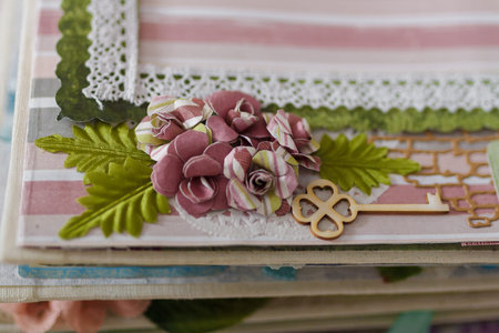 Soft focused close up shot of scrapbooking photo album page with paper decorative elements, flowers,...