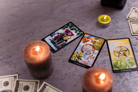 Divination cards alignment with money and green candles. Mystery, astrology, fortune telling, belief and wealth concept.の写真素材