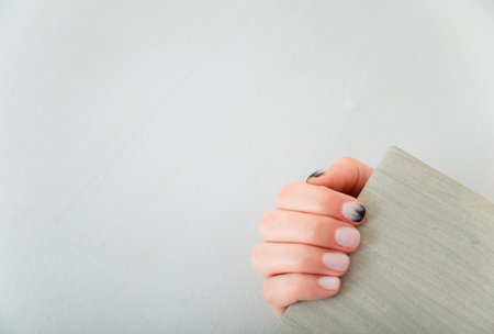 Female hands with fir-tree forest manicure holding leather covered album or notebook on white...