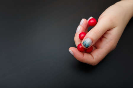 Female hands with fir-tree forest manicure holding red berries on black background. Christmas or winter nail art. Hands care, fingernails design, beauty and health concept. Copy space.の写真素材