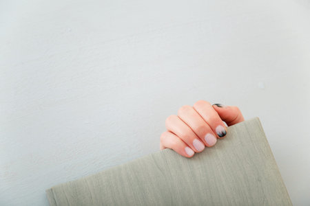 Female hands with fir-tree forest manicure holding leather covered album or notebook on white...