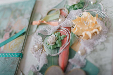 Soft focused close up shot of scrapbooking photo album page with paper decorative elements, flowers, hearts, ribbons, beads. Leisure and hobby concept.の写真素材