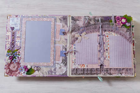 Scrapbooking wedding photoalbum spread with pink and purple paper decorative elements, flowers, beads, tapes, ribbons, hearts and frames for phographs.の写真素材