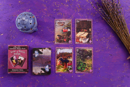 Divination cards alignment with oil burner and dry lavender on purple background. Mystery,...