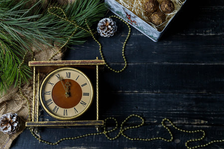 Brown and golden vintage clock, pine branches on black background. Merry Christmas, Happy New Year...