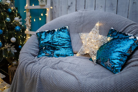 Christmas and New Year living room interior with decorated fir tree and blue armchair with pillows
